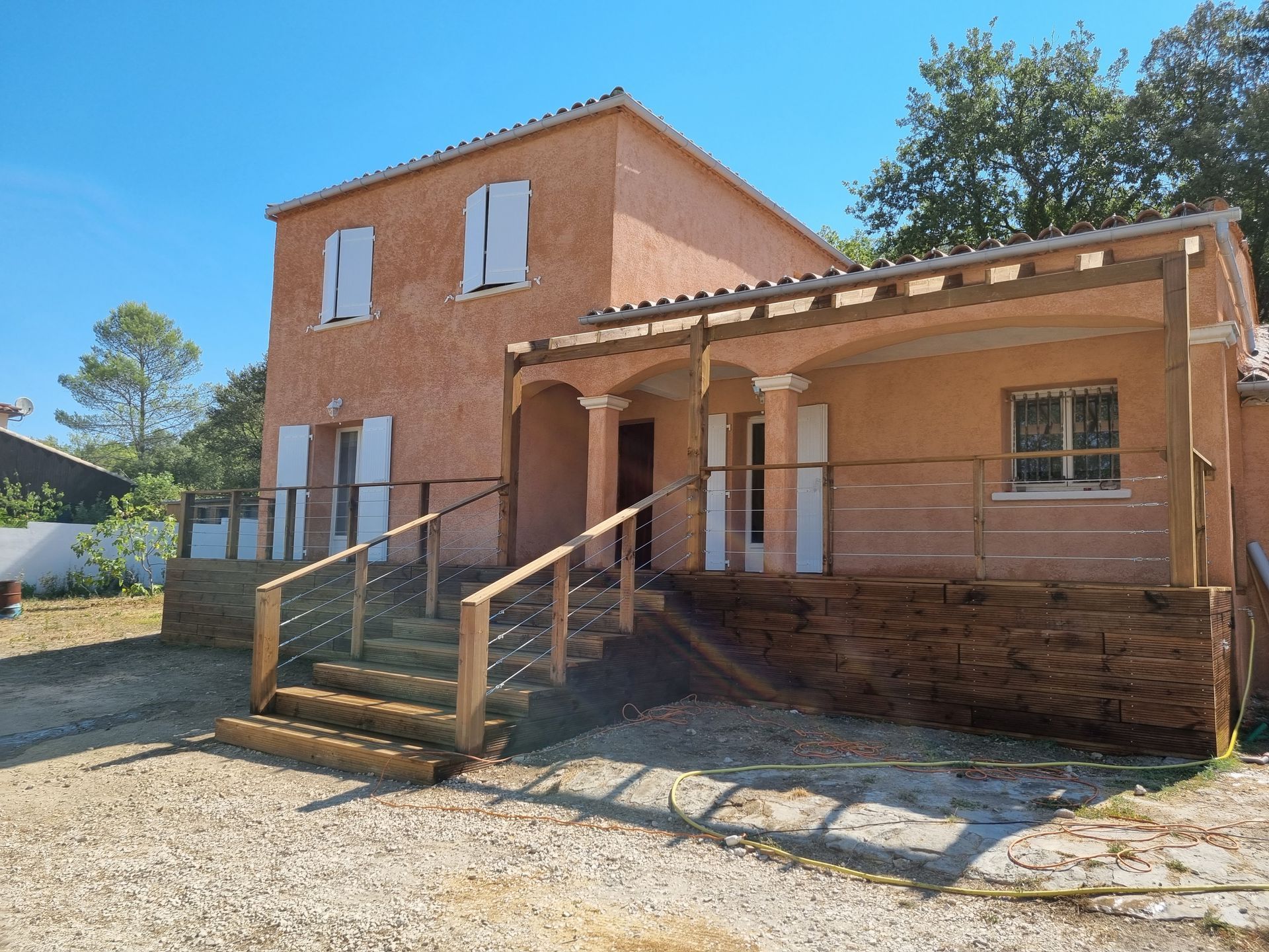 Maison en briques de deux étages avec porche, marches et rampe d'accès sous un ciel bleu clair