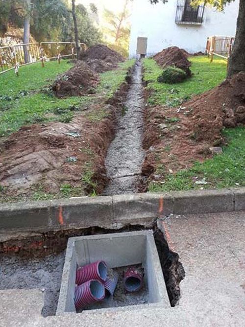 Se está instalando un desagüe en un patio al lado de una casa.