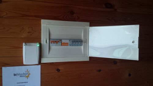 Una caja blanca está sobre un piso de madera al lado de un papel.