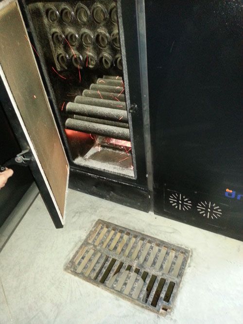 Hay una tapa de alcantarilla en el suelo junto a un refrigerador.
