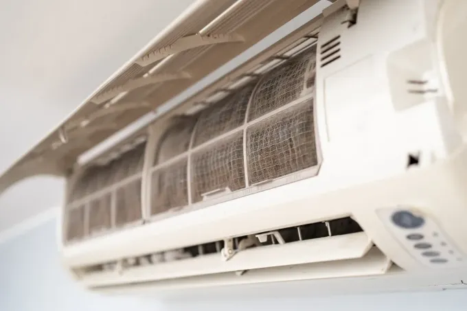 Un aparato de aire acondicionado blanco montado en la pared, con el panel frontal abierto.