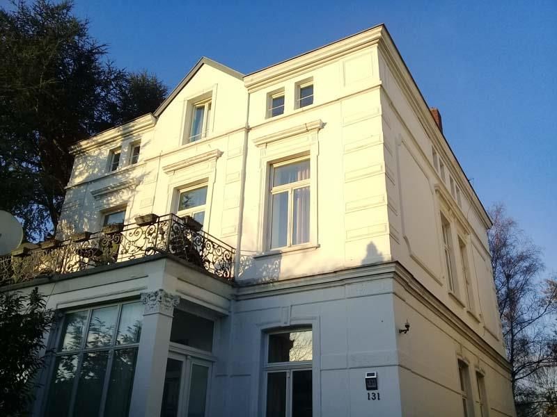 Ein großes weißes Gebäude mit einem Balkon und einem blauen Himmel im Hintergrund