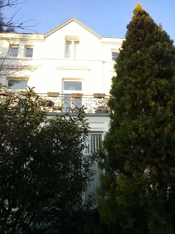 Ein weißes Haus mit einem Balkon und einem Baum davor