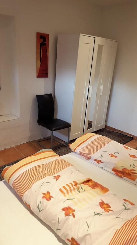Ein Schlafzimmer mit zwei Betten, einem Sessel und einem Kleiderschrank.