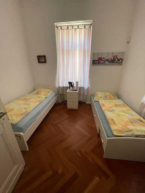 Ein Schlafzimmer mit zwei Betten, einem Nachttisch und einem Fenster.