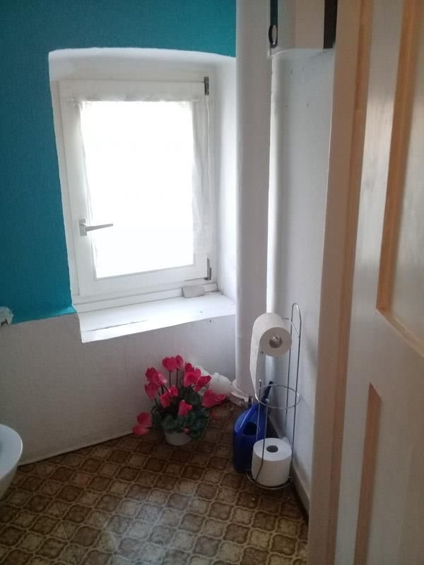 Ein Badezimmer mit Toilette, Fenster und einer Rolle Toilettenpapier.