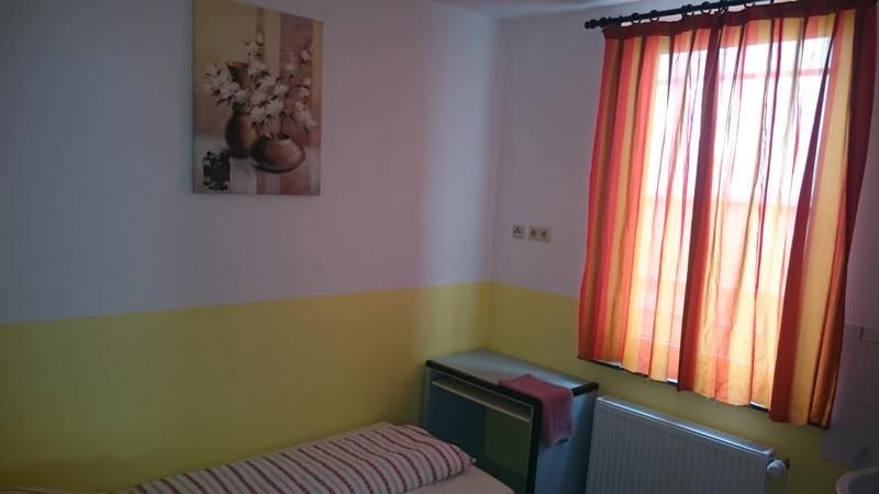 Ein Schlafzimmer mit einem Bett und einem Fenster mit orangefarbenen Vorhängen.