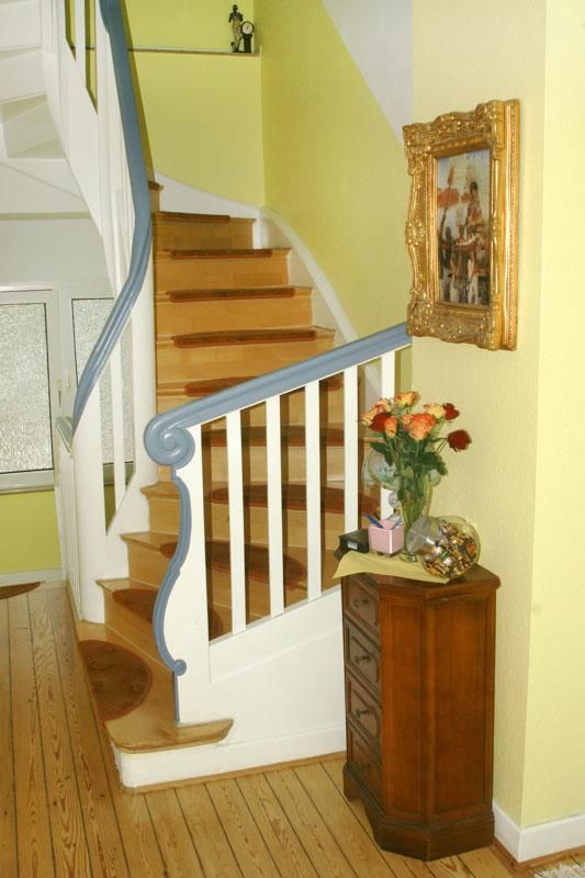Eine Holztreppe mit blauem Geländer und einem Bild an der Wand darüber