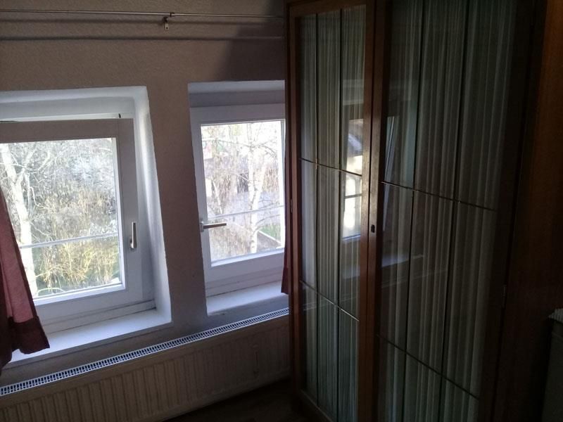 Ein Zimmer mit Fenster und Schrank mit Blick auf Bäume