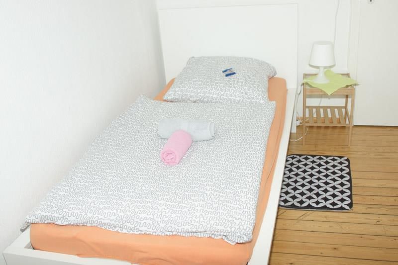 Ein Schlafzimmer mit Einzelbett, Nachttisch und Lampe.