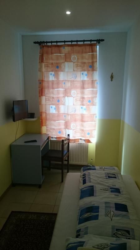 Ein kleines Schlafzimmer mit Bett, Schreibtisch, Stuhl und Fernseher.