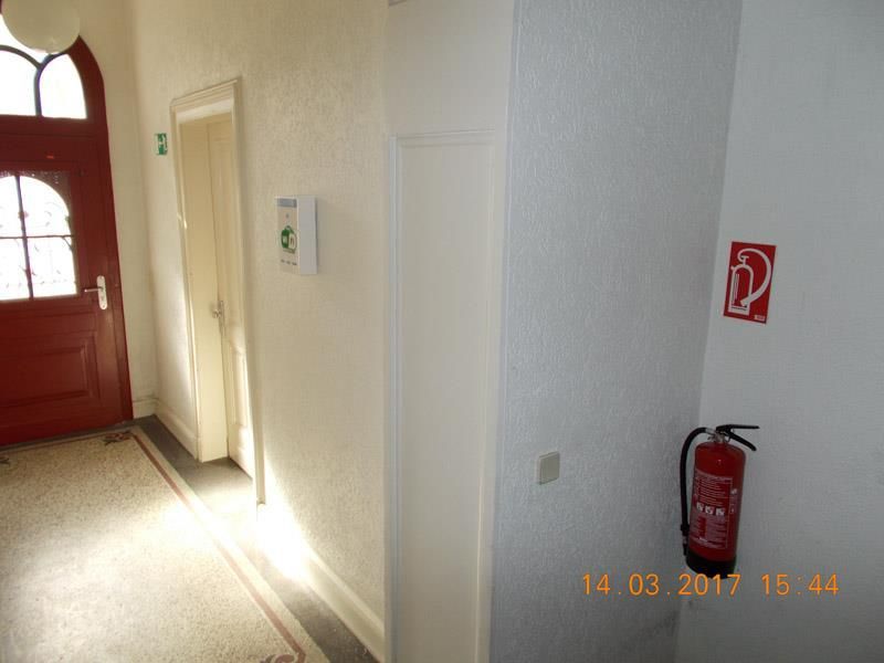 Ein Flur mit einer roten Tür und einem Feuerlöscher an der Wand