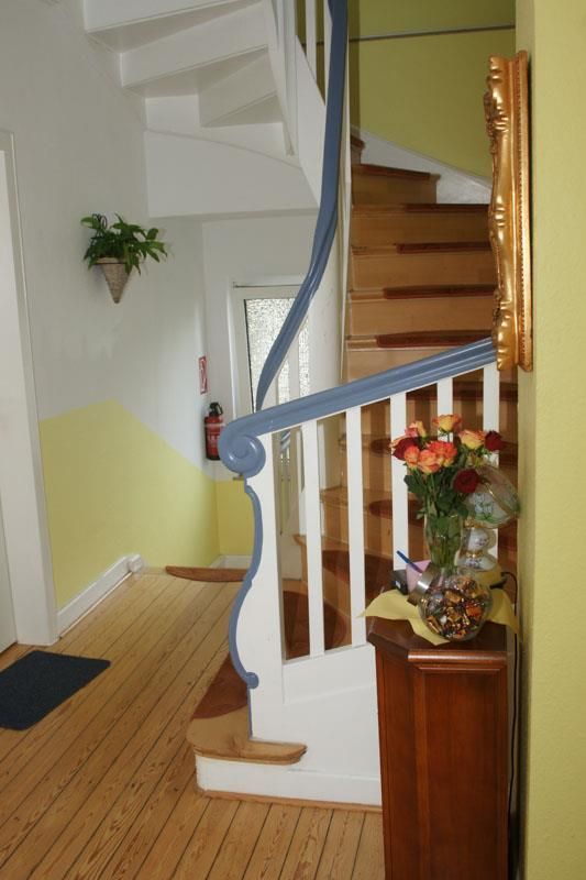 Ein Flur mit einer Treppe und einer Vase mit Blumen