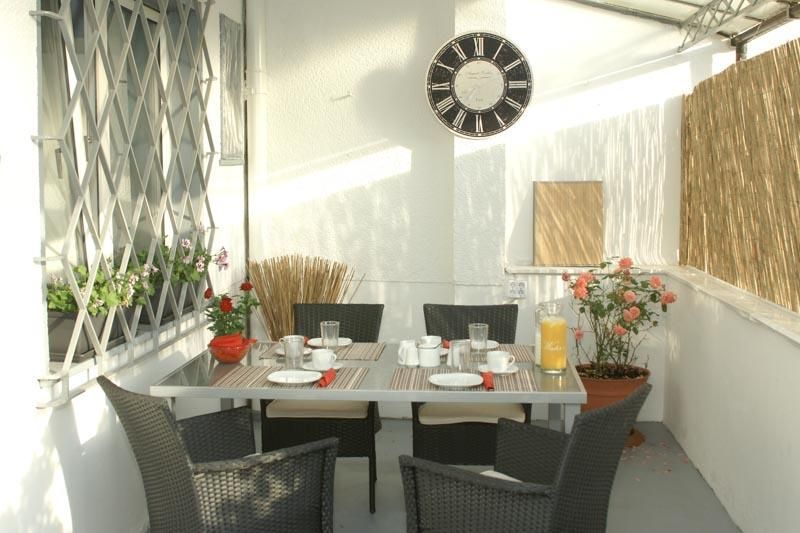 Eine Terrasse mit Tisch und Stühlen und einer Uhr an der Wand