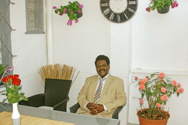 Ein Mann in Anzug und Krawatte sitzt vor einer Uhr