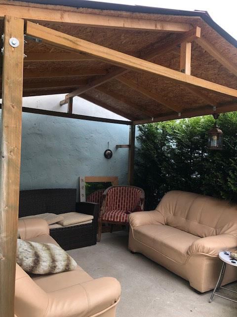 Eine Pergola mit einer Couch und Stühlen darunter