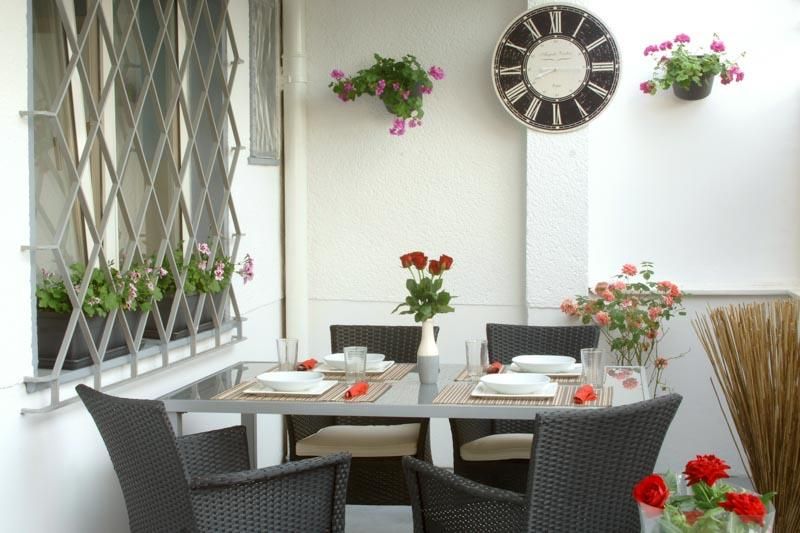 Eine Terrasse mit Tisch und Stühlen und einer Uhr an der Wand
