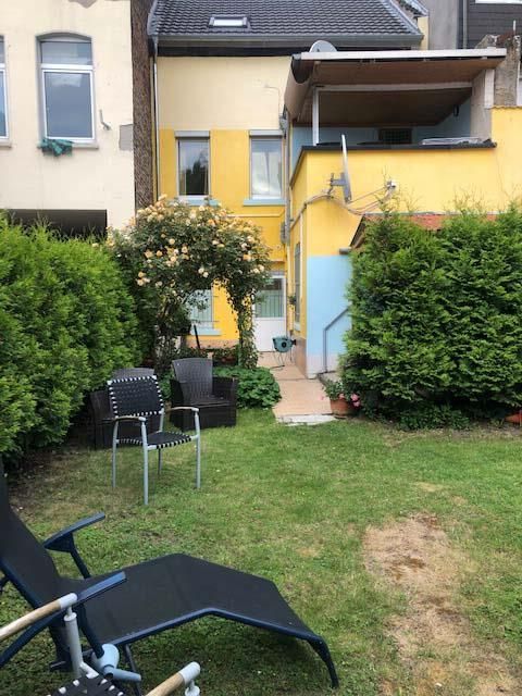 Ein Hinterhof mit Gartenstühlen und einem gelben Gebäude im Hintergrund