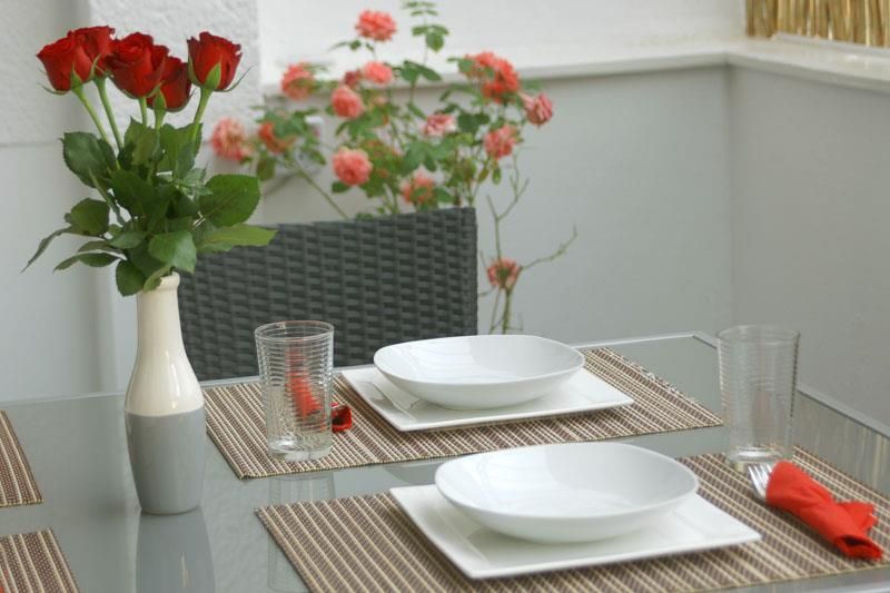 Ein Tisch mit Tellern, Gläsern und einer Vase mit Blumen darauf