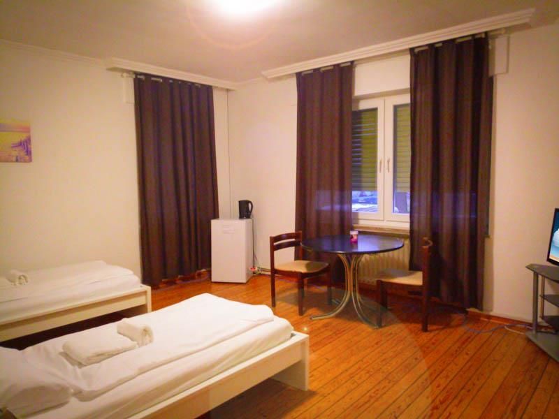 Ein Schlafzimmer mit zwei Betten, einem Tisch, Stühlen und einem Fernseher.
