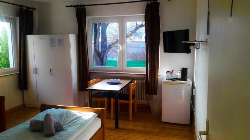 Ein Schlafzimmer mit Bett, Tisch, Stühlen und Fernseher.