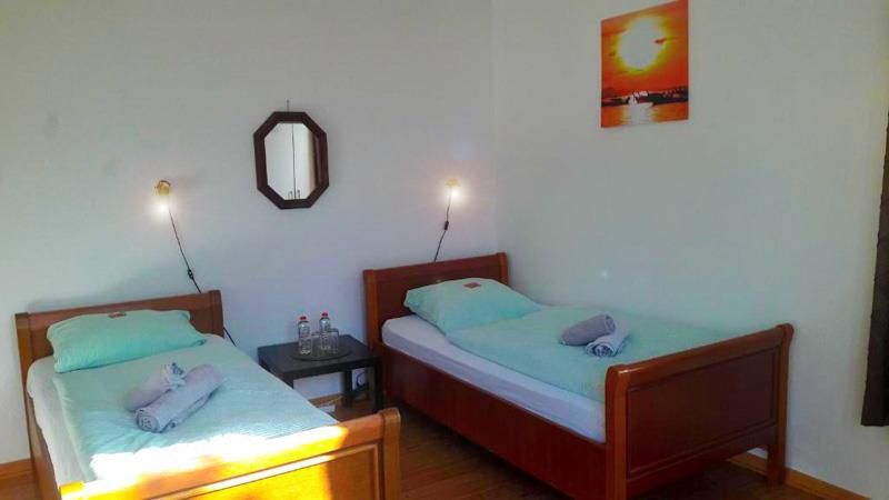 Ein Schlafzimmer mit zwei Betten, einem Spiegel und einem Gemälde an der Wand.