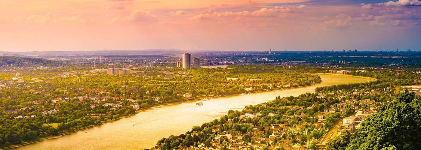 Eine Luftaufnahme eines von Bäumen umgebenen Flusses und einer Stadt bei Sonnenuntergang.