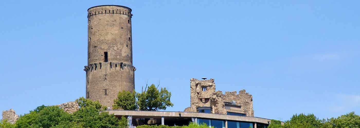 Auf einem Hügel steht ein großer Turm, umgeben von Bäumen.