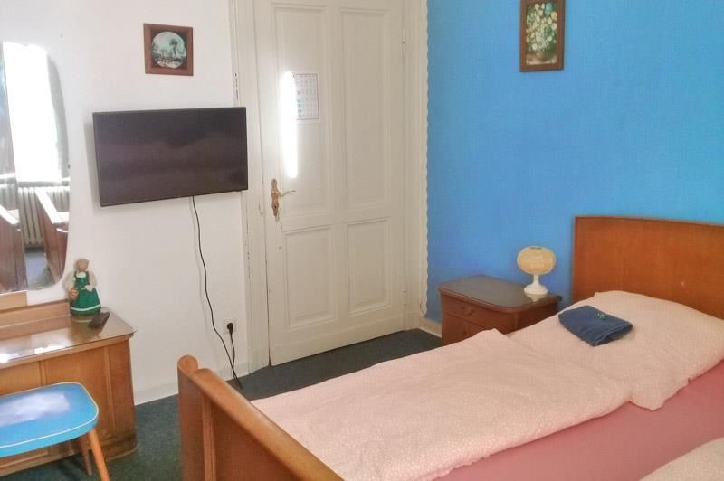 Ein Schlafzimmer mit Bett, Kommode, Fernseher und Spiegel.