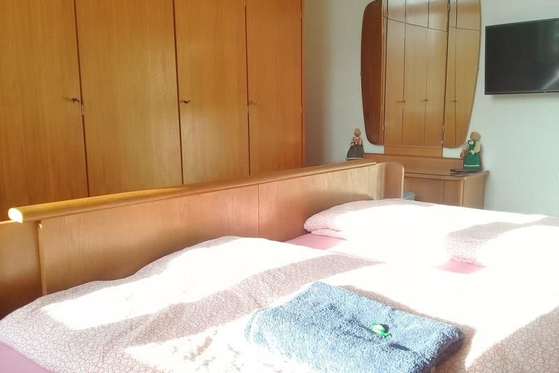 Ein Schlafzimmer mit Bett, Kommode, Spiegel und Fernseher.