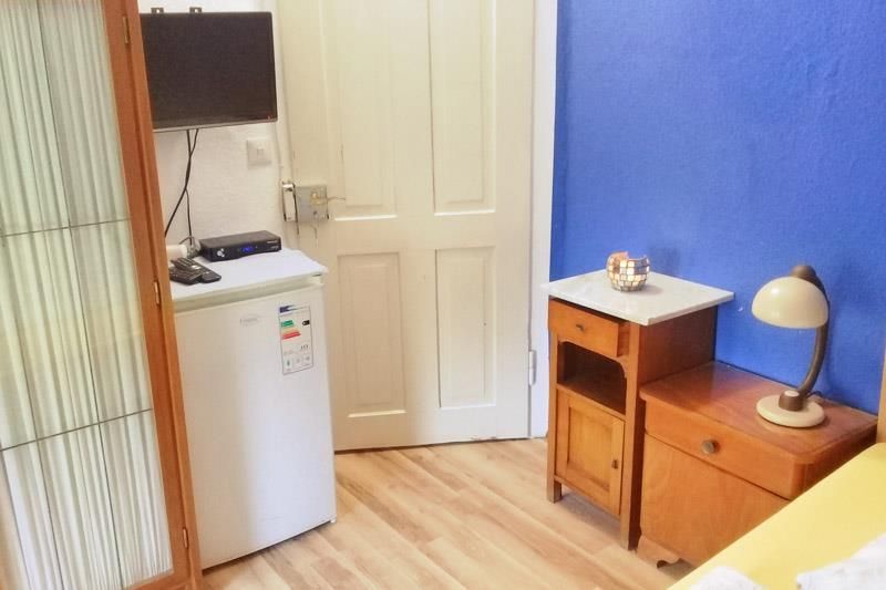 Ein Schlafzimmer mit Bett, Nachttisch, Kühlschrank und Fernseher.