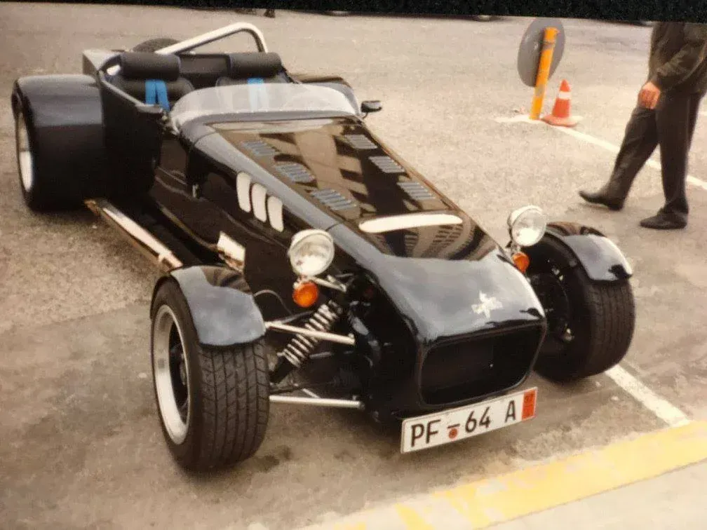 Automóvil roadster negro estacionado, detalles cromados, llantas con borde blanco, matrícula 