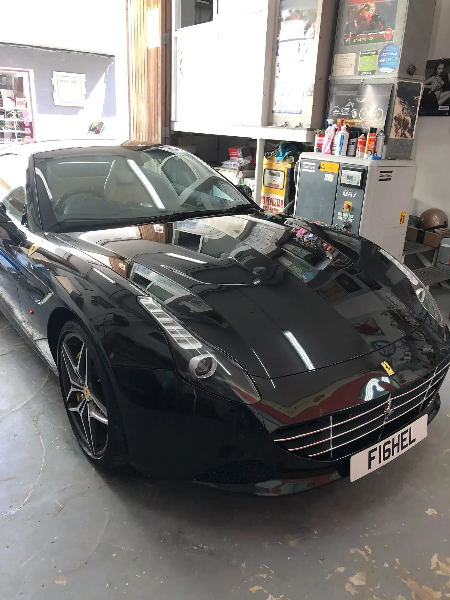 Ferrari negro descapotable en un garaje.