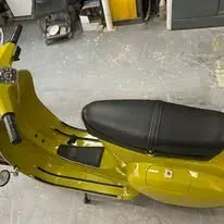 Scooter Vespa amarillo con asiento negro.