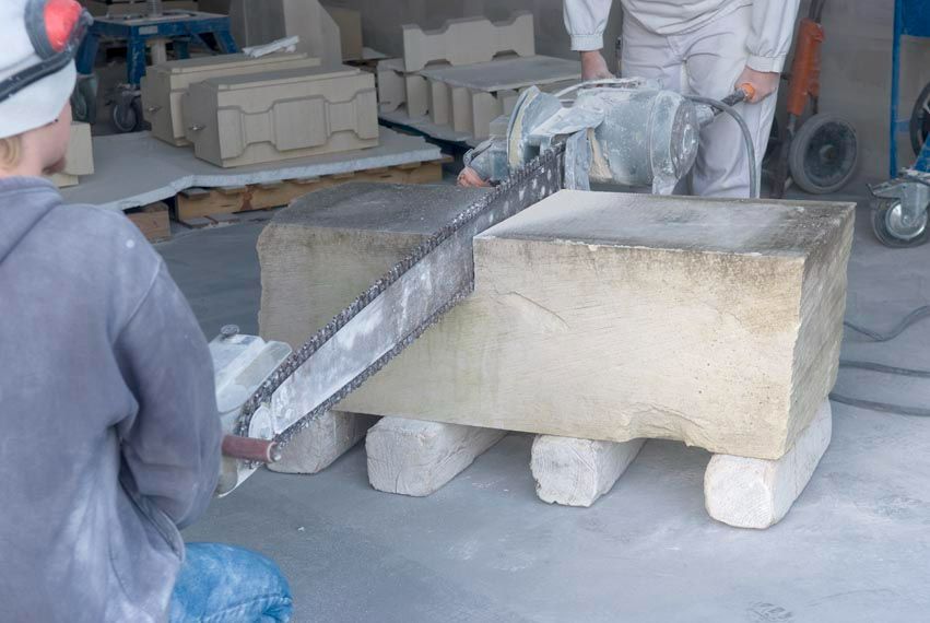 Découpe d'une grosse pierre à la scie par deux employés