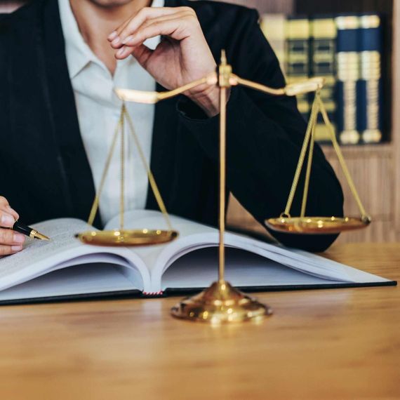 Un hombre está sentado en un escritorio con un libro y una balanza de justicia.