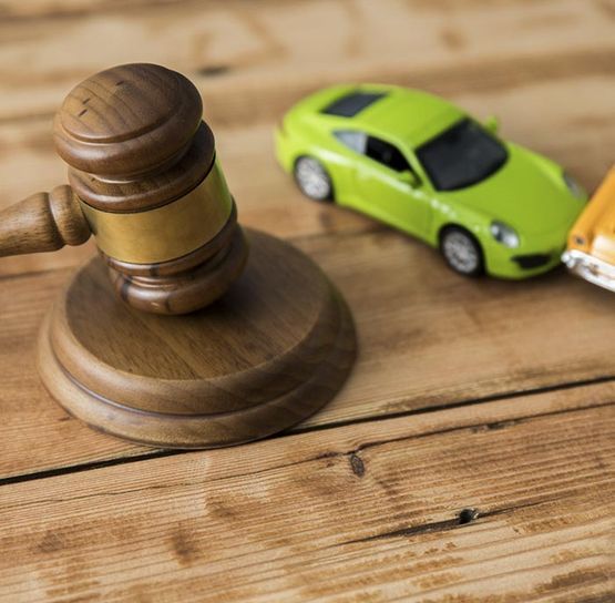 El mazo del juez junto a coches de juguete sobre una mesa de madera.