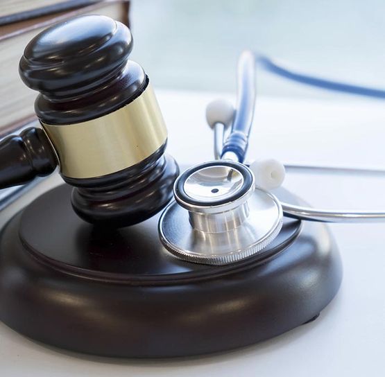 Mazo de juez junto a un estetoscopio sobre una mesa, que simboliza el derecho médico o los litigios en el ámbito de la salud.