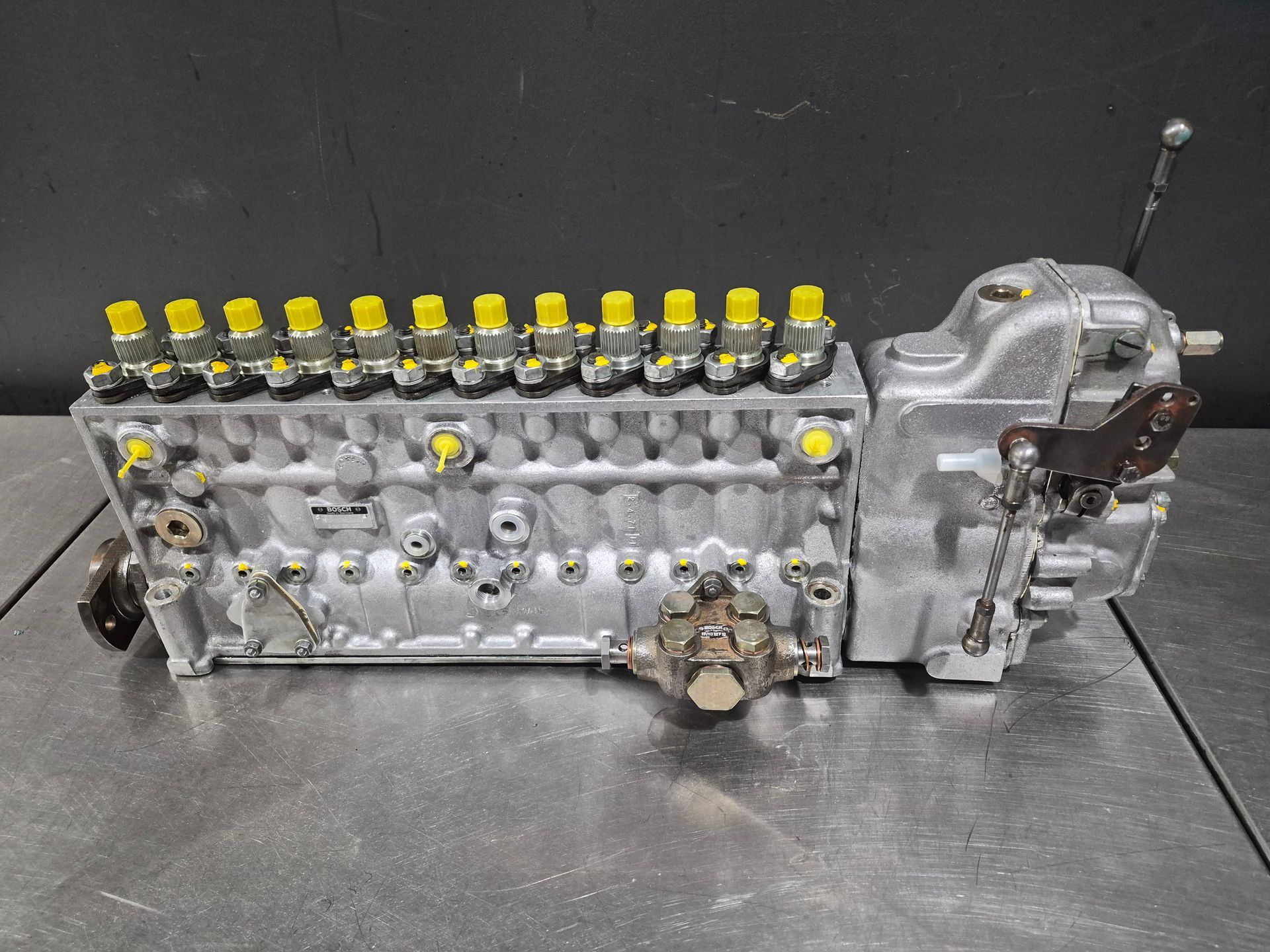 Moteur diesel avec plusieurs injecteurs jaunes et boîte de vitesses. Métal gris sur une table.