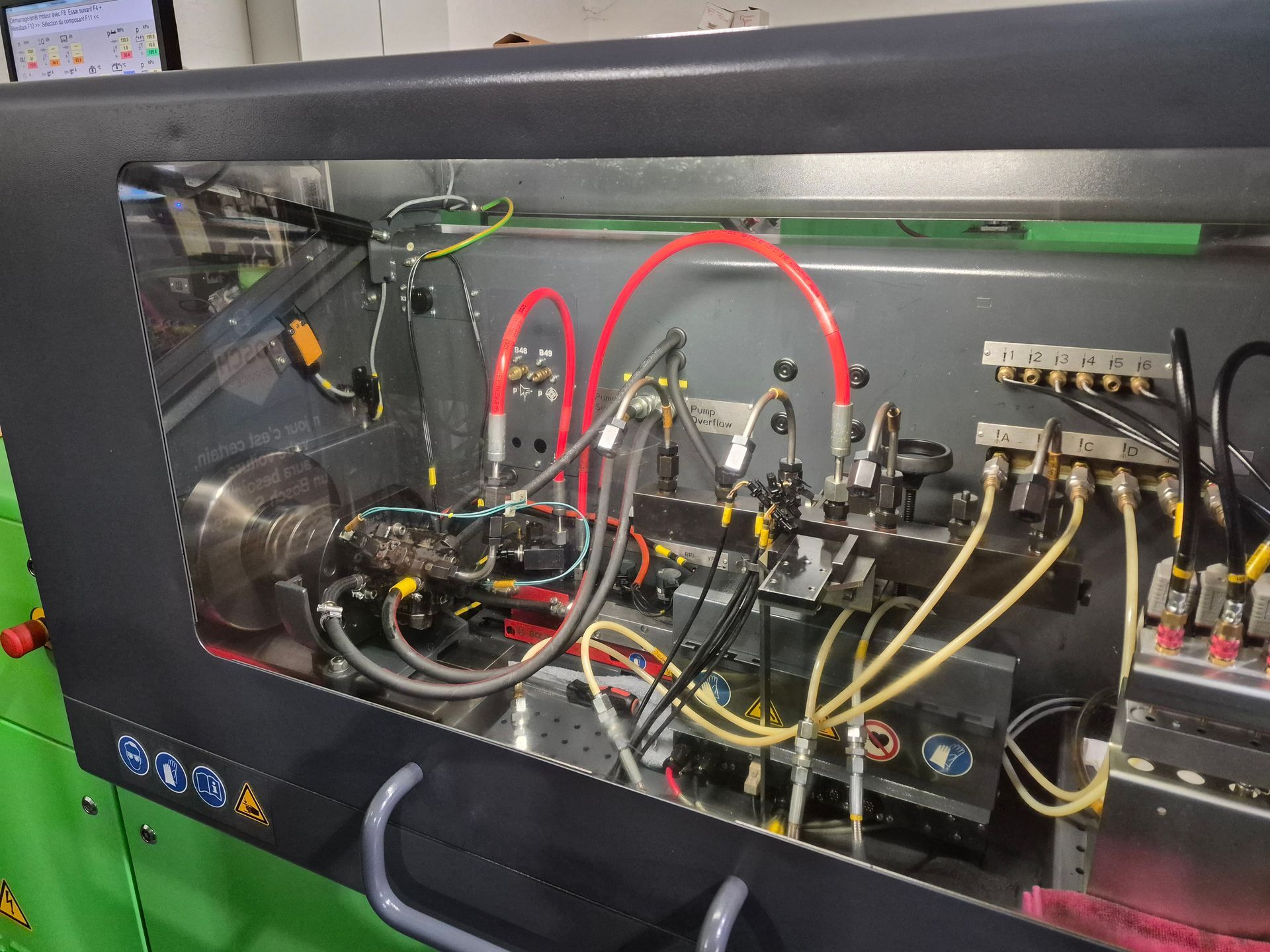 Intérieur d'un banc d'essai d'injection de carburant diesel vert avec divers tubes, fils et composants.