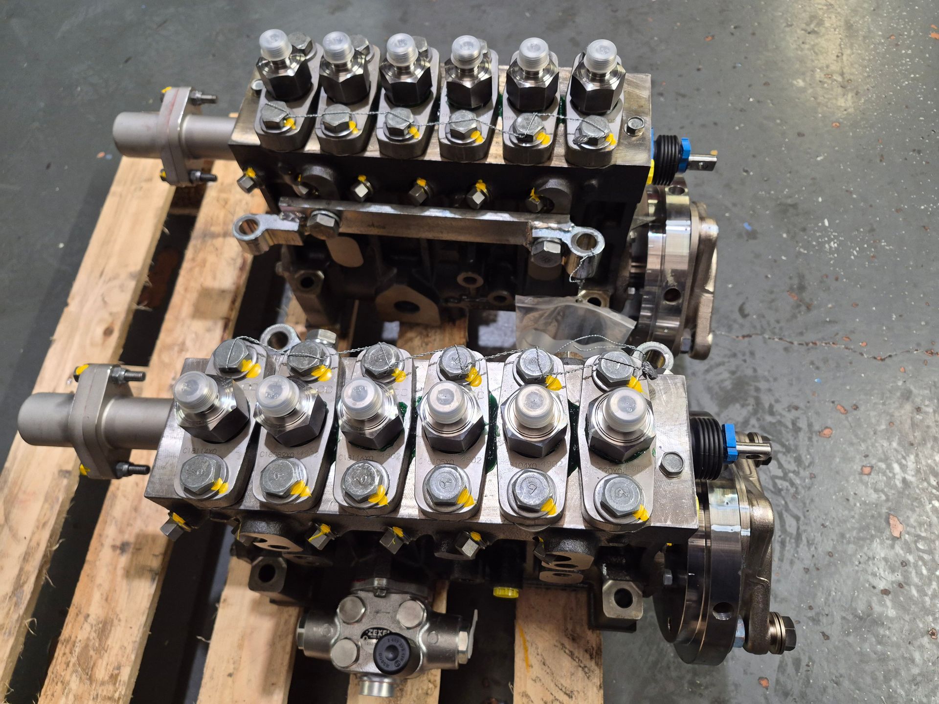 Deux pompes à carburant diesel industrielles sur une palette en bois ; des machines métalliques complexes avec de nombreux boulons et raccords.