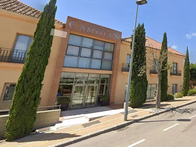 Un edificio beige de dos plantas con puertas de cristal y el nombre 