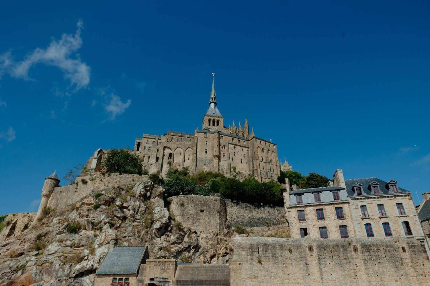 Mont Saint-Michel, Normandía, Francia, una abadía medieval en lo alto de una isla rocosa, bajo un cielo azul brillante.