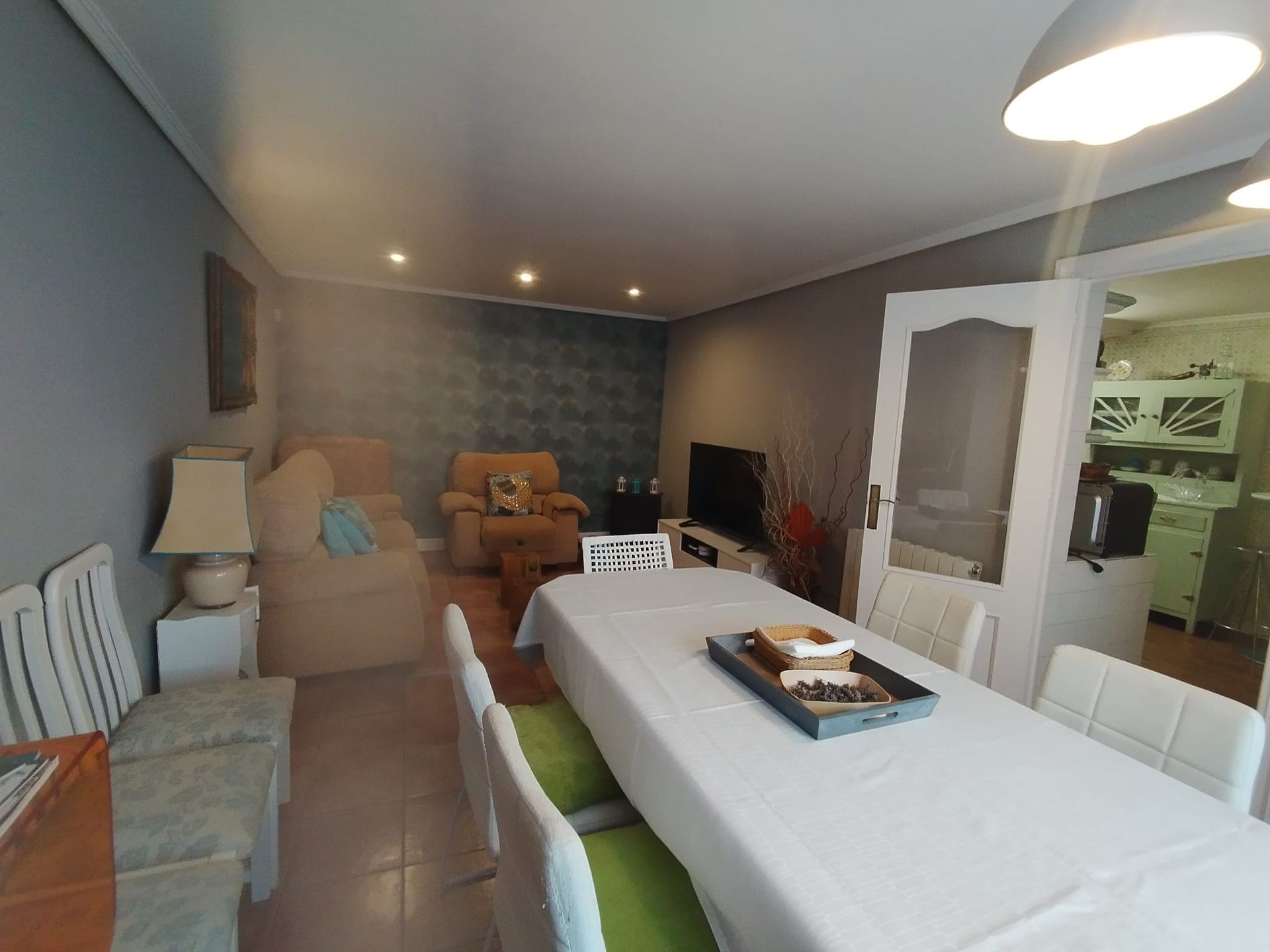 Comedor con mesa larga, sillas, sofá y televisión.