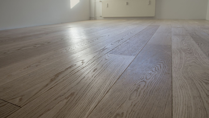 Parquet en bois finition brillante, couleur marron clair, dans une pièce aux murs blancs et avec un placard.