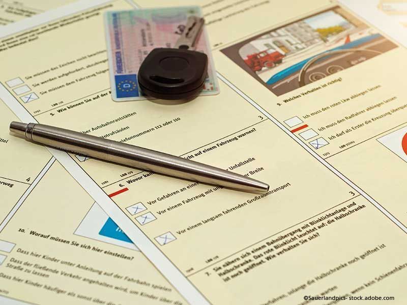 Führerschein, Autoschlüssel und Stift liegen auf einem Formular für die Fahrprüfung.