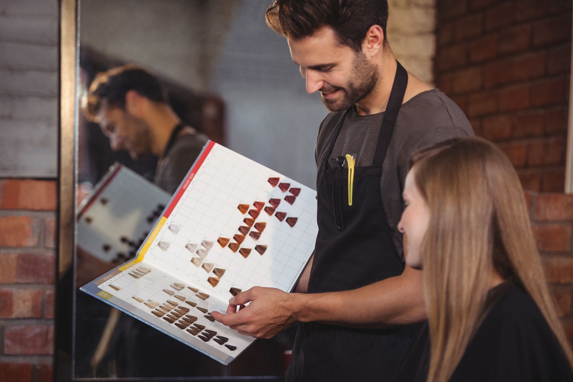 Dans un salon de coiffure, une coiffeuse professionnelle présente un nuancier à une cliente.