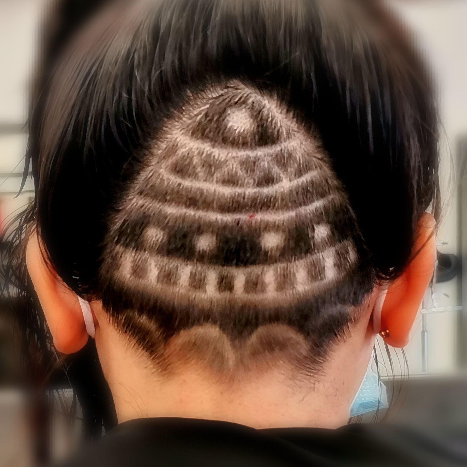 Une nuque dégagée avec un motif géométrique semi-circulaire en dégradé, sculpté dans des cheveux foncés.