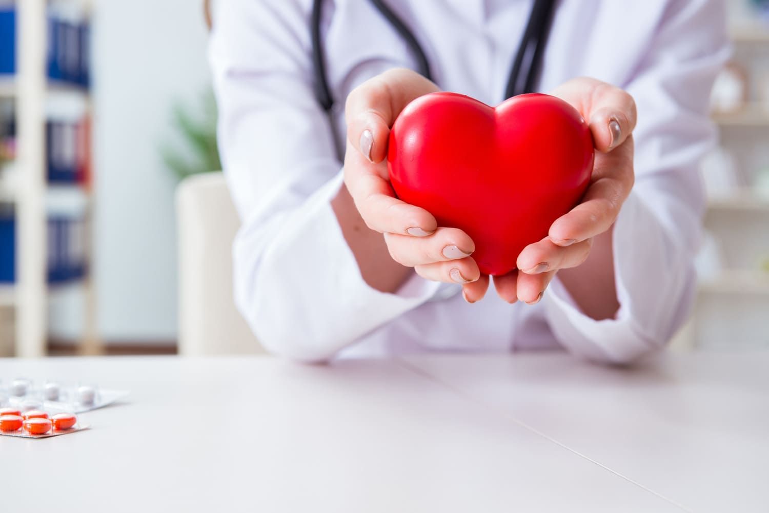 Un médico sostiene un corazón rojo en sus manos.