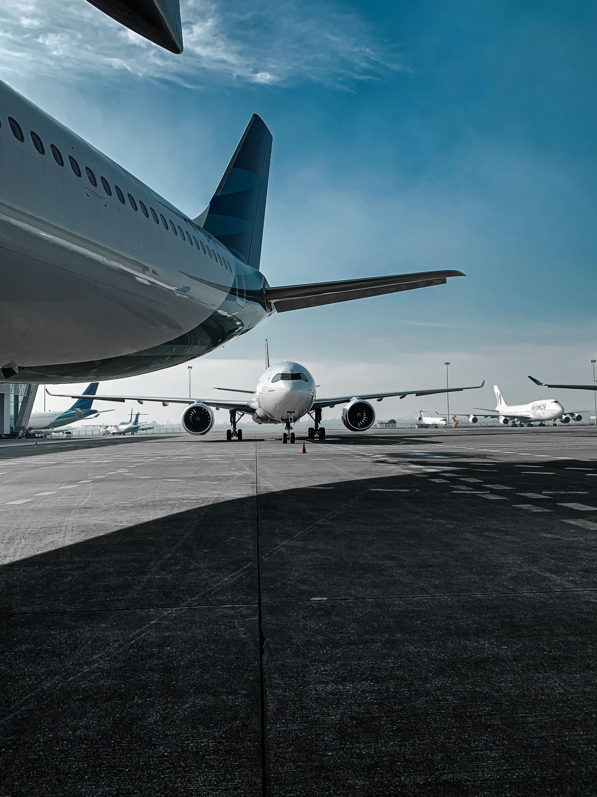 Des avions stationnés sur le tarmac d'un aéroport sous un ciel bleu nuageux